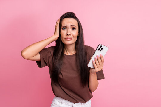 Portrait of woman wear t shirt touch head dissatisfied hackers send her anonymous content using phone isolated on pink color background