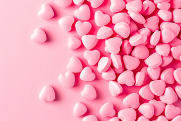 Closeup of pink candy hearts and sweets in shape of love symbol on pink background, for Valentine's day