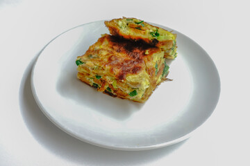 Martabak Telur or Egg Martabak is Savory pan-fried pastry stuffed with egg, meat and spices on white plate isolated on white background . Martabak Telur is one of Indonesia street food