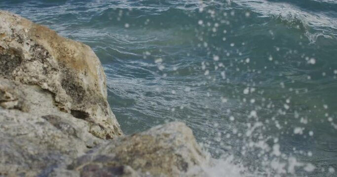waves and wind splashing against a rock in the ocean