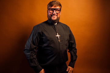 Portrait of a priest with crucifix and black shirt holding a bible.