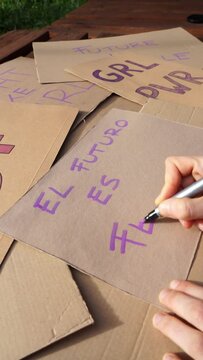 Woman writing a feminist banner with the phrase: The future is feminist in Spanish for the March 8 demonstration