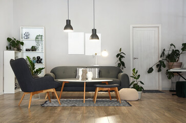 Interior of stylish living room with grey sofa, armchair and glowing lamps at evening