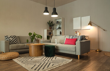 Interior of stylish living room with grey sofas and glowing lamps at evening