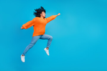 Fototapeta na wymiar Full body photo of attractive young woman jump run have fun hurry dressed stylish knitted orange clothes isolated on blue color background