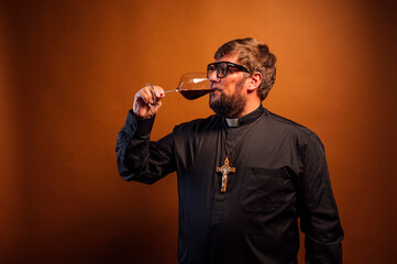 Portrait of a priest with crucifix and sunglasses drinking wine.