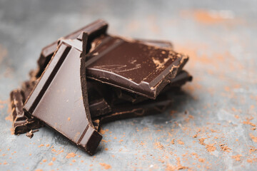 Heap of delicious dark chocolate pieces or cubes, chopped, broken chocolate bar on a dark background