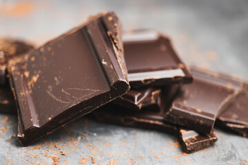 Heap of delicious dark chocolate pieces or cubes, chopped, broken chocolate bar on a dark background