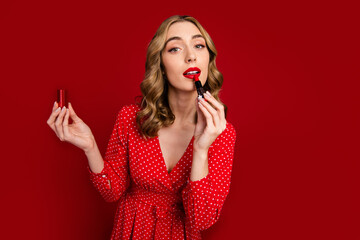 Photo of lovely elegant lady hold apply lipstick empty space advert isolated on vibrant red color background