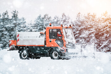 Road maintenance in winter. a tractor equipped with a spreader sprays a salt and sand mixture on...