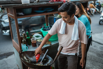 Fototapeta na wymiar indonesian man putting sauce on fried rice, street food concept