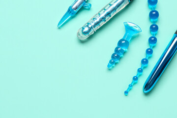 Different anal plugs and vibrators from sex shop on turquoise background - obrazy, fototapety, plakaty