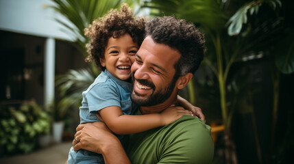 Homem brasileiro vestindo roupas verdes abraçando seu filho e sorrindo  - obrazy, fototapety, plakaty