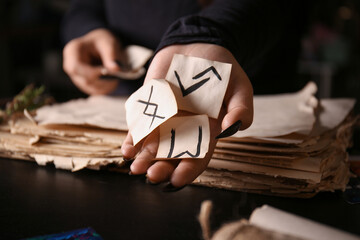 Witch with runes at dark table, closeup