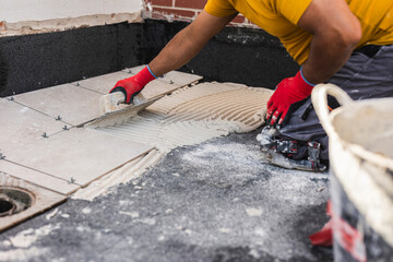 worker laying tiles on the floor with cement - obrazy, fototapety, plakaty
