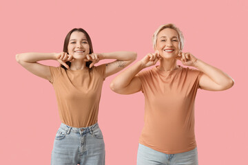 Beautiful women doing face building exercise on pink background