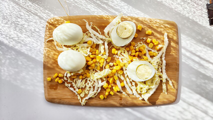 Chopped Peking cabbage, peeled eggs and yellow canned corn on cutting board as a background....