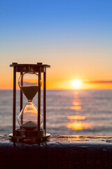 Hourglass or sand timer in front of a beatiful clear sunrise or sunset.