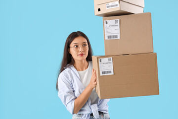 Young Asian seller with parcels on blue background