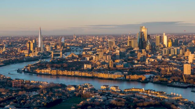 Beautiful sunrise timelapse view of the urban skyline of London, England, with soft orange sunlight reflecting at the skyscrapers