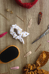 Wooden hairbrush, scissors and various headbands, hair clips and scrunchies on wooden background. Flat lay.