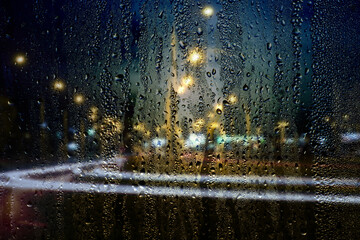 Rainy window, raindrops on the glass on the background of the freeway. Safe way home.
