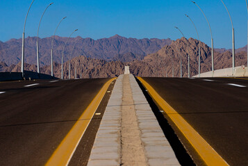 Asphalt roadbed stretching into the distance with mountains and sky, Sinai, Egypt.