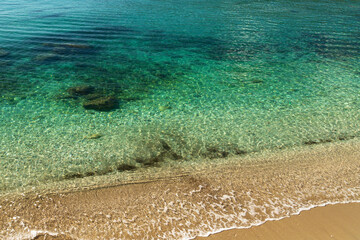Coastline of the Adriatic Sea in Montenegro. Rippling waves crash on the shore. Emerald water.
