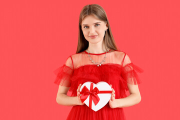 Beautiful woman with gift box on red background. Valentine's Day celebration