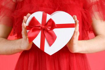 Beautiful woman with gift box on red background, closeup. Valentine's Day celebration