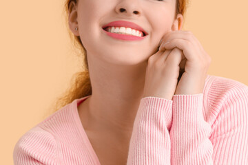 Smiling young redhead woman on beige background, closeup