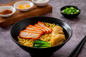 Egg noodle with red roasted pork and wonton in black bowl