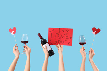 Women holding paper with text I LOVE YOU, wine and hearts on blue background. Valentine's Day...