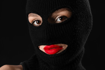 Beautiful young stylish woman in balaclava on black background