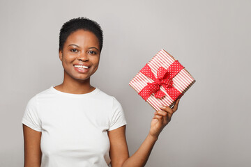 Attractive happy young woman with gift present box standing on white background