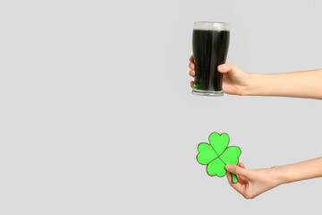 Hands with beer and shamrock on light background. St. Patrick's Day celebration