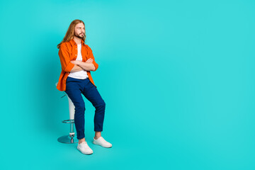 Full size photo of confident guy wear stylish outfit sit on stool look at proposition empty space...