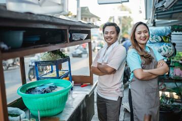 asian couple standing behind traditional food cart with crossed arm