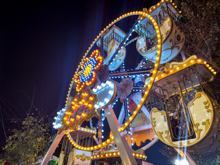 Wheel shaped carousel with lights at a fair.