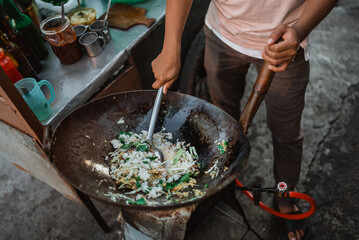 male hand stirring indonesian fried rice in the wok