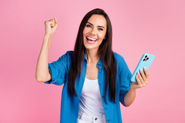Photo of satisfied ecstatic girl dressed blue shirt holding smartphone win bet scream raising fist...
