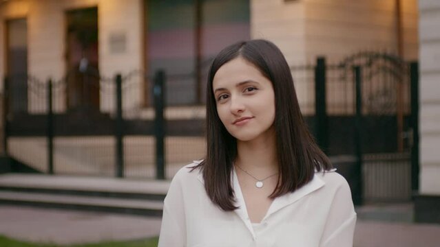 Young happy woman looks and smiles at camera. Female on shooting day in office clothes.
