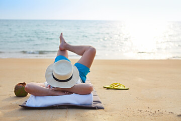 Man in the hat with coconut cocktail on the beach