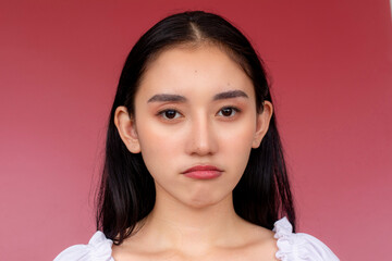 Portrait of a disappointed young asian woman with a subtle pouting expression, set against a...