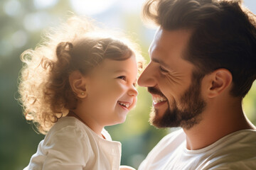 Close-up of a smiling father and his daughter in a sunlit setting.