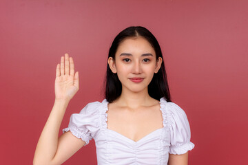 Portrait of a poised young Asian woman with a raised hand, making an oath and pledging loyalty....