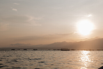 Warm peach sunrise over tropical island. Beautiful seascape and view of fishing boats.