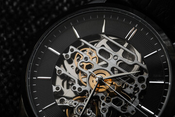 Macro photo of mechanic skeleton watch. Black clock face