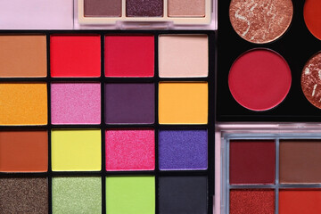 Various colorful eyeshadow palettes on bright pink background. Flat lay.