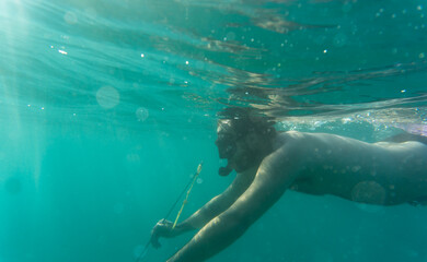 Underwater view of a man swimming with a hawaiian speargun.Spain.